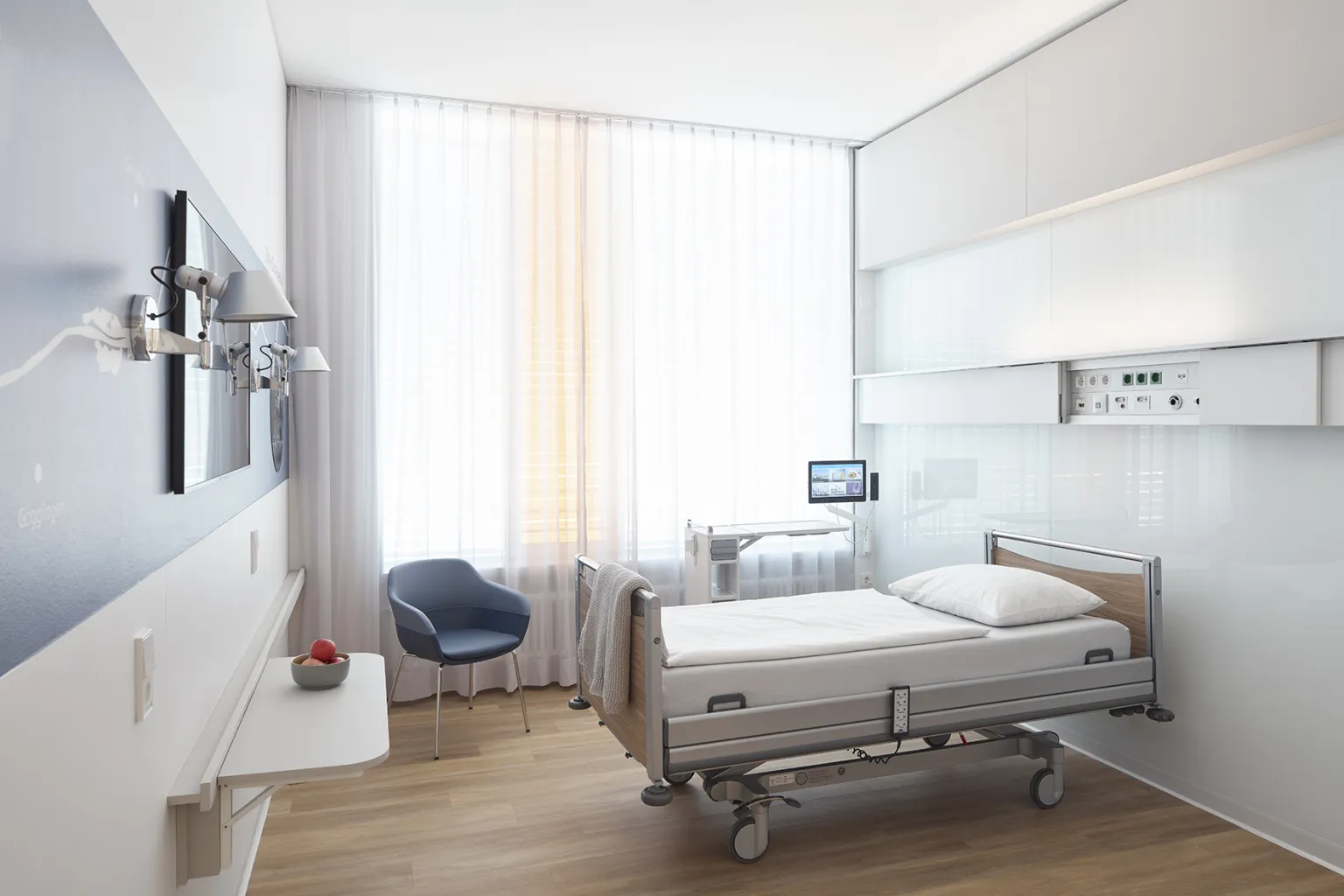 Im Hintergrund sieht man eine medizinische Versorgungseinheit in einem Wahlleistungszimmer