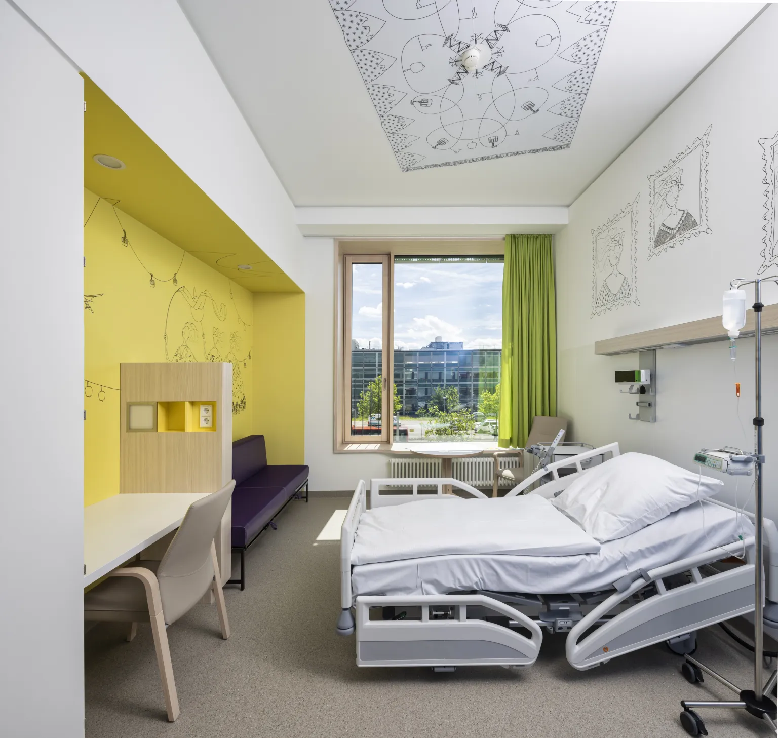 Krankenhauszimmer mit verstellbarem Bett, Schreibtisch, Stuhl, lila Sofa, gelber Wandnische mit Zeichnungen, Fenster mit grünem Vorhang und Wandzeichnungen an der Decke und Wand