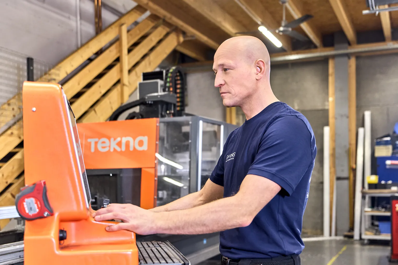 A worker stands at a CNC milling machine.