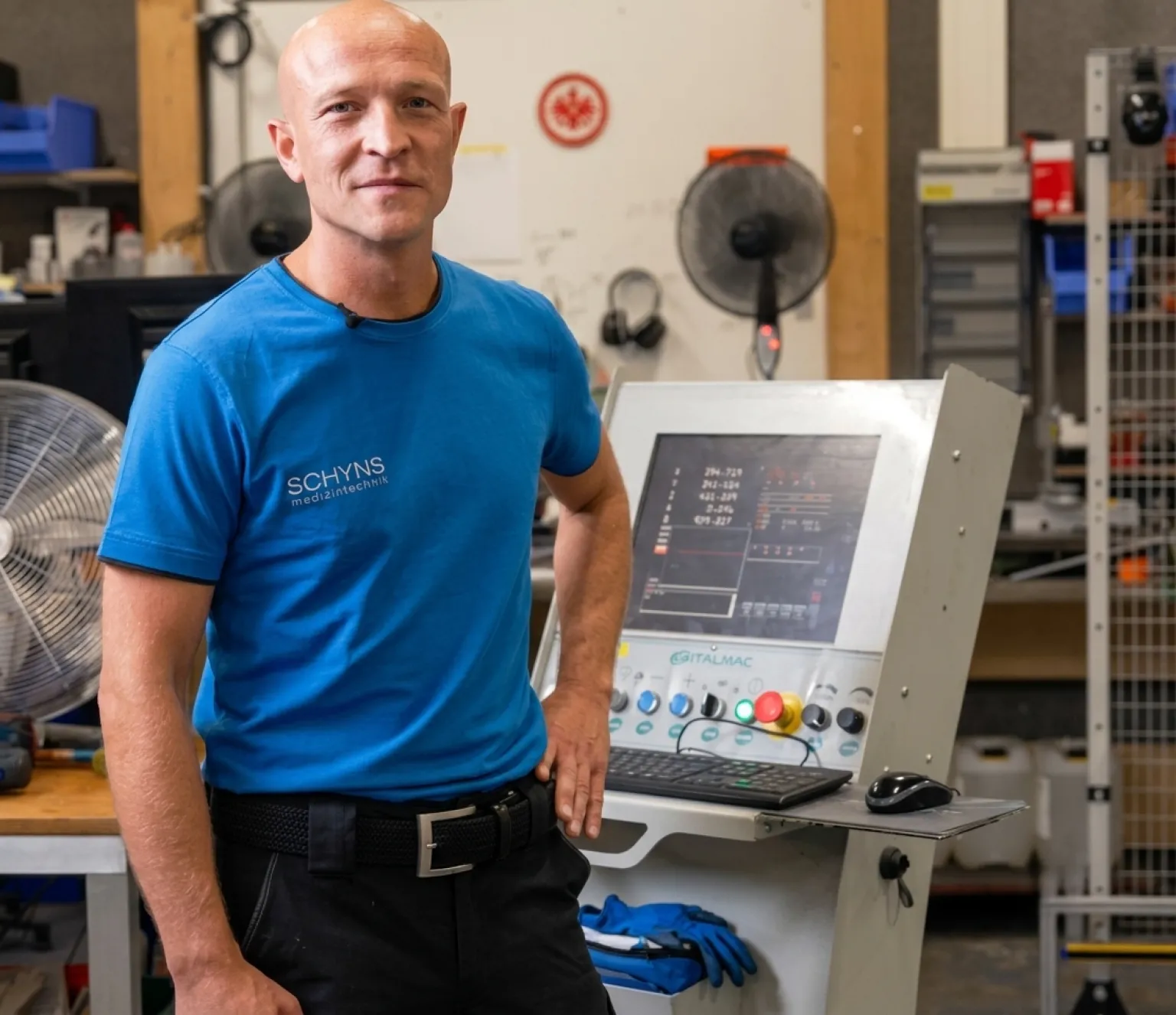 Man in blue T-shirt working on CNC machine in workshop
